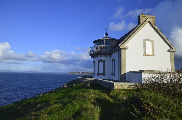 A coastal building with a tower, a balcony, and a view of the sea.