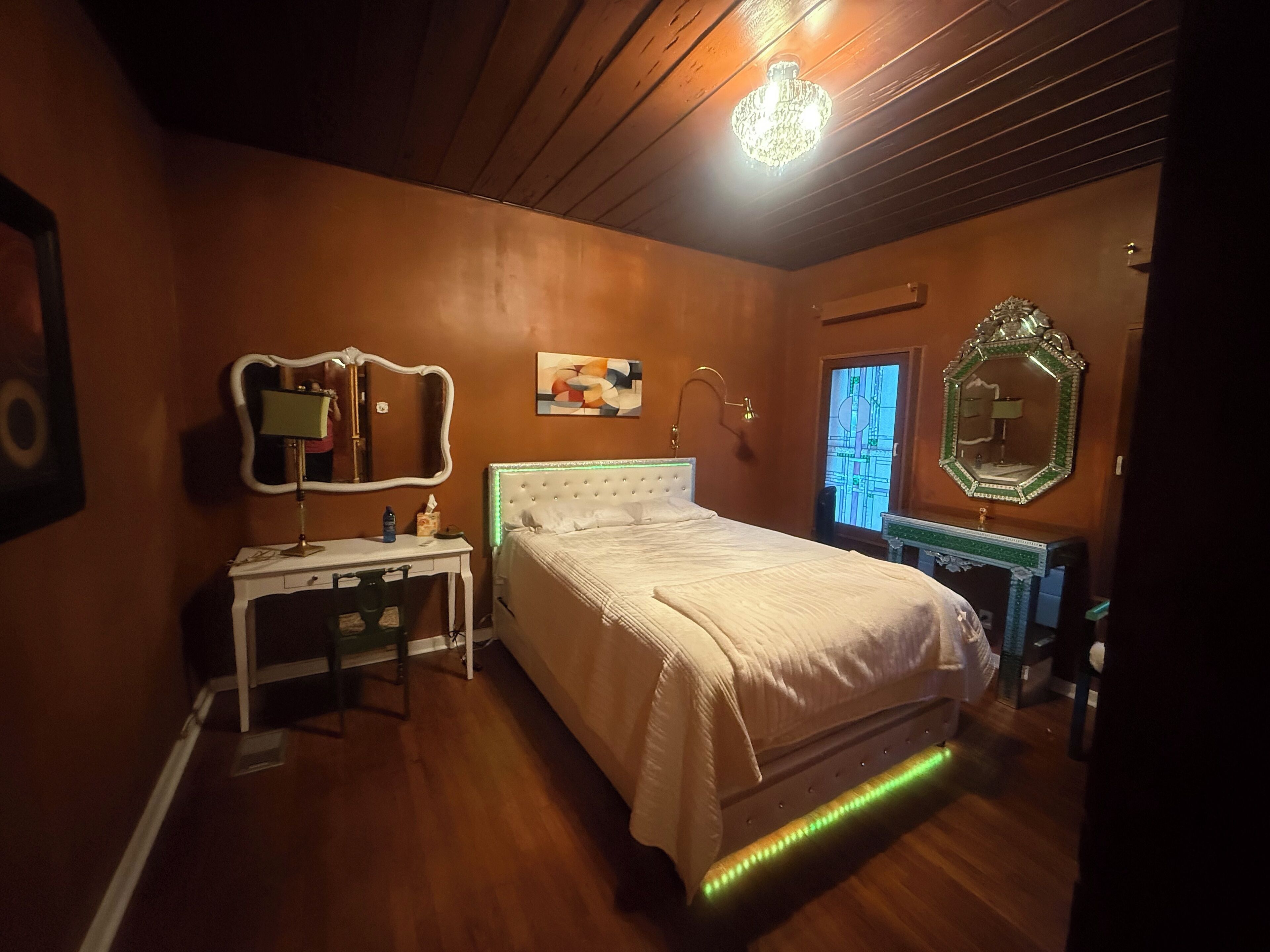 Ein Schlafzimmer mit einem Bett, einem Schreibtisch, einem Spiegel und einer Kommode.