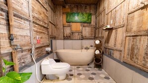 A bathroom with a wooden interior, a bathtub, a toilet, and a sink. - Room-deluxe Double or Twin Room (Ubud)