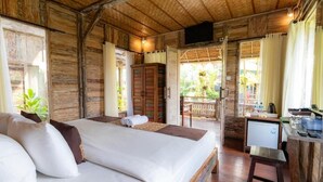 A wooden room with a bed, a desk, and a television. - Room-deluxe Double or Twin Room (Ubud)