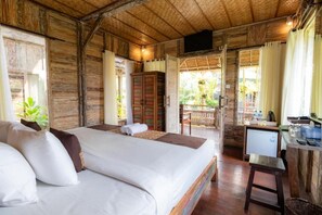 A wooden room with a bed, a desk, and a television. - Room-deluxe Double or Twin Room (Ubud)