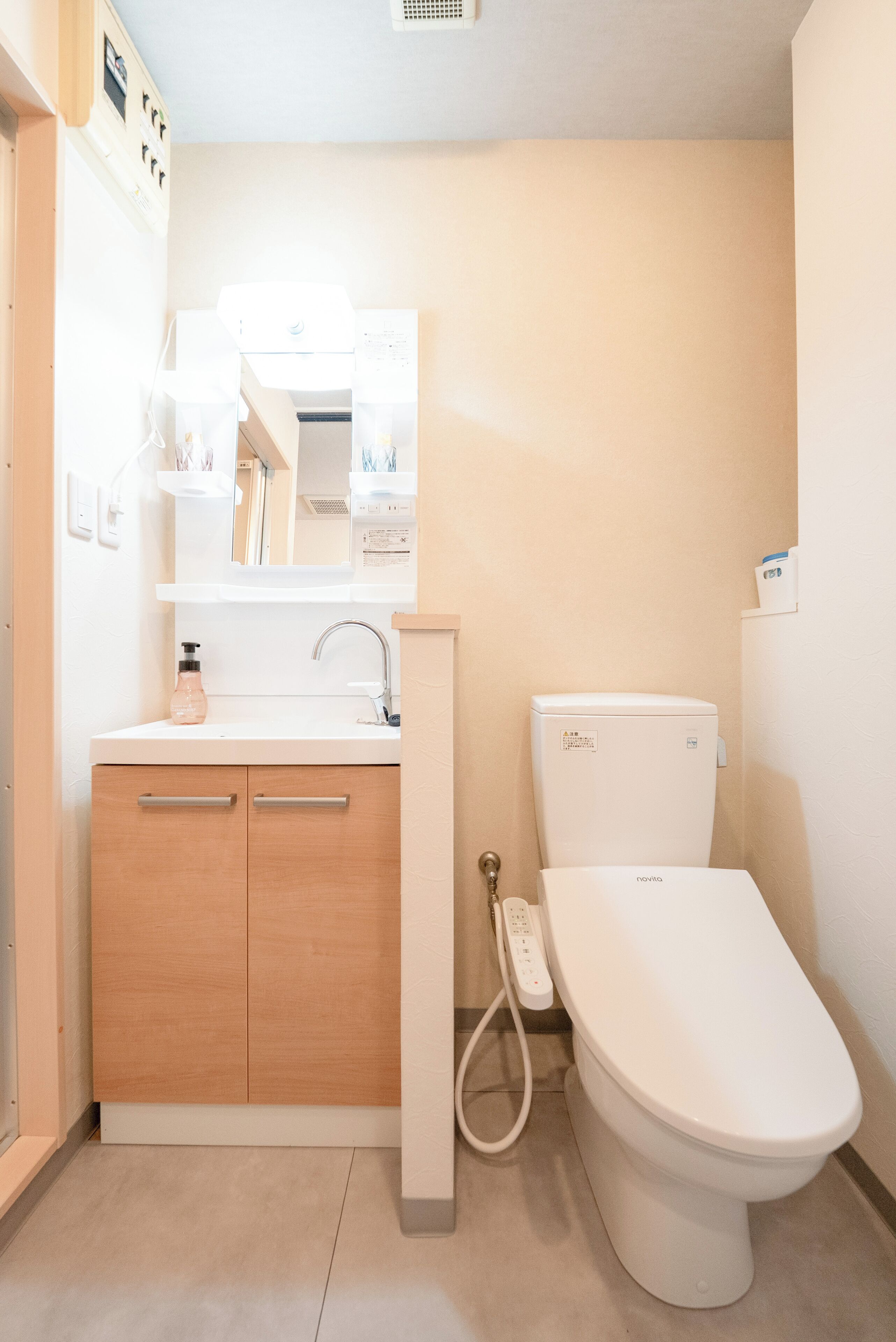 Uma casa de banho compacta com sanita, lavatório com espelho e móvel com gavetas.