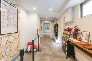 Eine Hotelhalle mit einer Rezeption, einer Steinwand, einer Karte und einem Flur, der zu einem Aufzug führt.