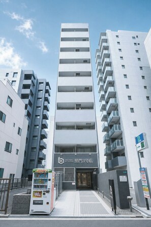 A modern building with a prominent entrance, a vending machine, and a parking sign. - b&Kuromon 3 (Osaka)