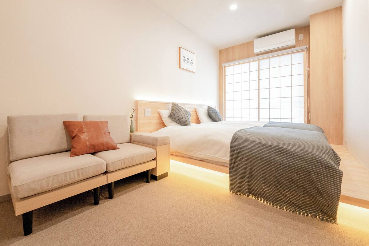 A modern bedroom with a sofa, a bed, and a window.