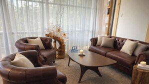 A modern living room with two brown leather sofas, a round coffee table, and a decorative centerpiece. - Gió Homestay Villa (Xuan Huong - Da Lat)