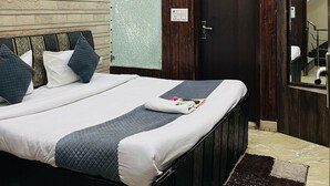 Un dormitorio con cama, ventilador de techo, puerta de madera y espejo.