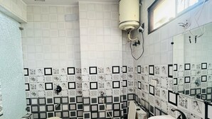 Un baño con inodoro, lavamanos y ducha. Las paredes están cubiertas de cerámica con un diseño geométrico.