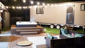 Un jardin avec un jacuzzi, un coin salon extérieur et des guirlandes lumineuses.