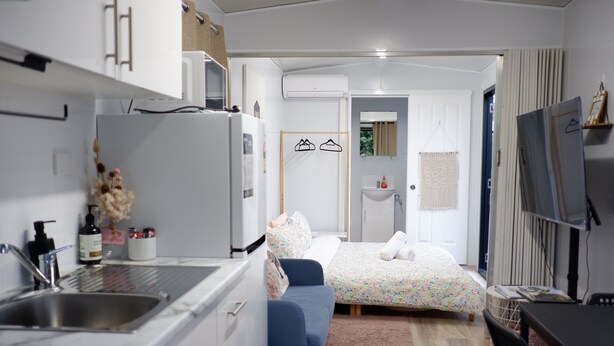 Une chambre à coucher de taille réduite, comprenant un lit, une table de chevet et un petit bureau avec une chaise.