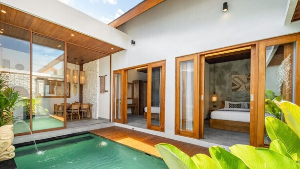 Une maison moderne dotée d’une piscine, de planchers en bois et de grandes portes vitrées donnant sur une chambre.