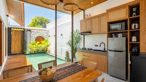 Une cuisine moderne avec des meubles en bois, un réfrigérateur en acier inoxydable et un coin repas comprenant une table et des chaises en bois.
