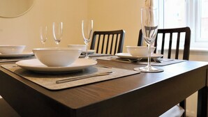 Taula de dinar coberta amb bols blancs, plats i gots de vi, amb cadires al voltant.