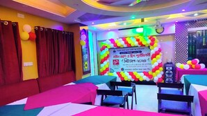Une chambre d’hôtel avec un espace aménagé en scène pour un événement, agrémenté d’une banderole et de ballons.