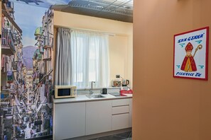 A kitchen with a window, a microwave, a coffee bar, and a wall with a poster. - Casa Calume   I Vicoli di Napoli (Naples)