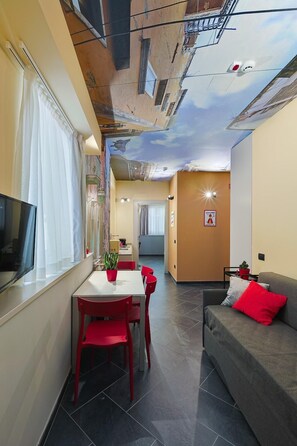 A modern interior with a dining area, a sofa, and a TV. - Casa Calume   I Vicoli di Napoli (Naples)