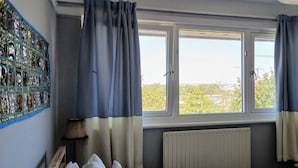 Habitació amb dues finestres, un radiador, una làmpada i una cadira.