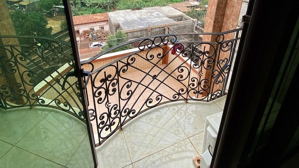 A balcony with a view of a cityscape, including buildings and greenery. - BALATSIT HOTEL HOTEL (Bafoussam)
