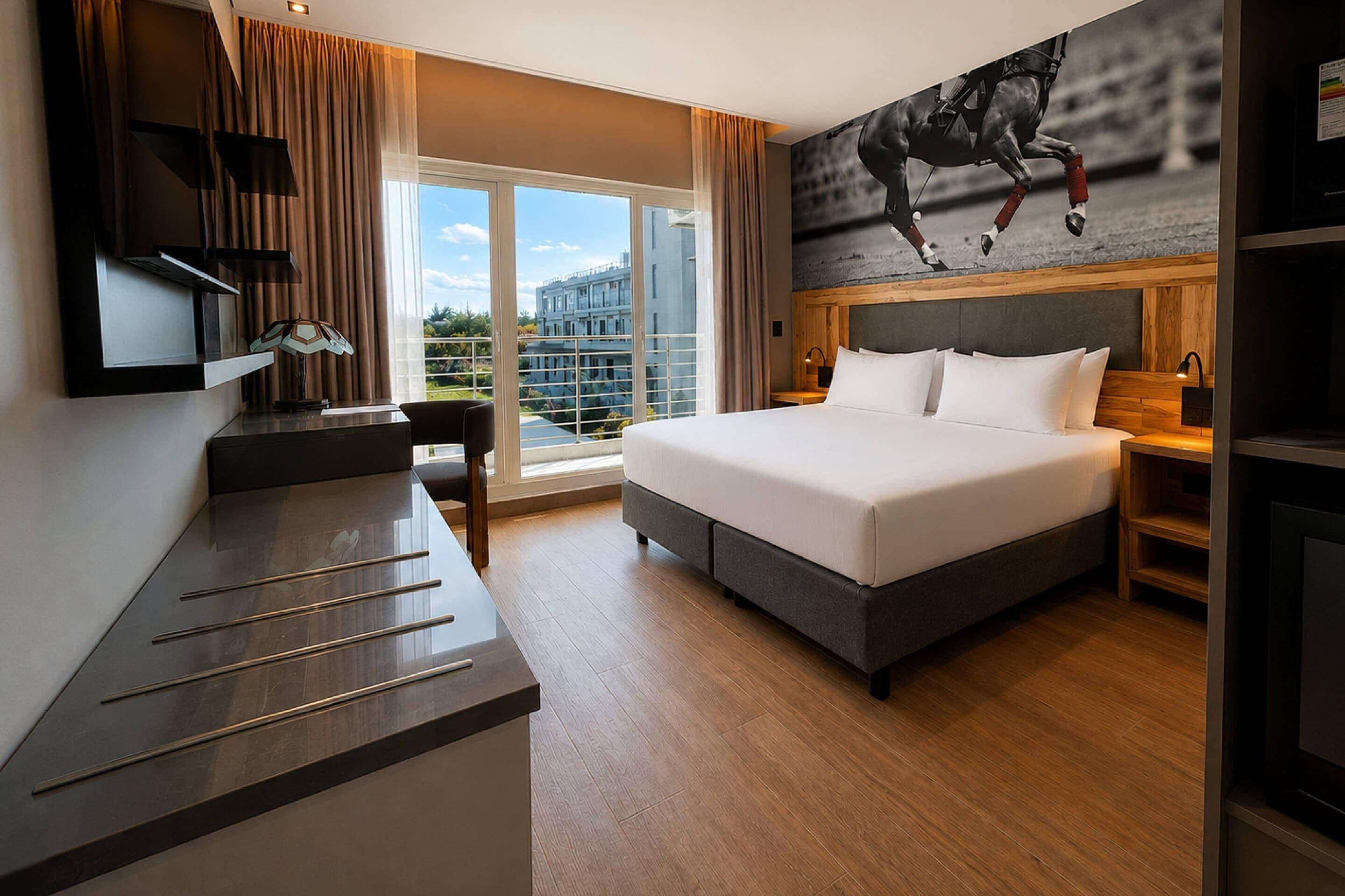 Ein Hotelzimmer mit einem großen Bett, einem Schreibtisch, einem Fernseher und Blick ins Freie.