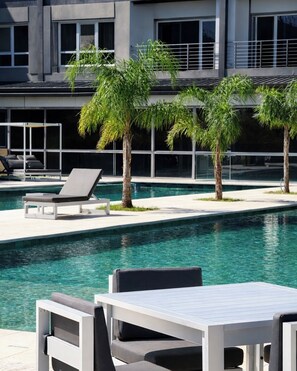 A modern pool area with lounge chairs and palm trees.