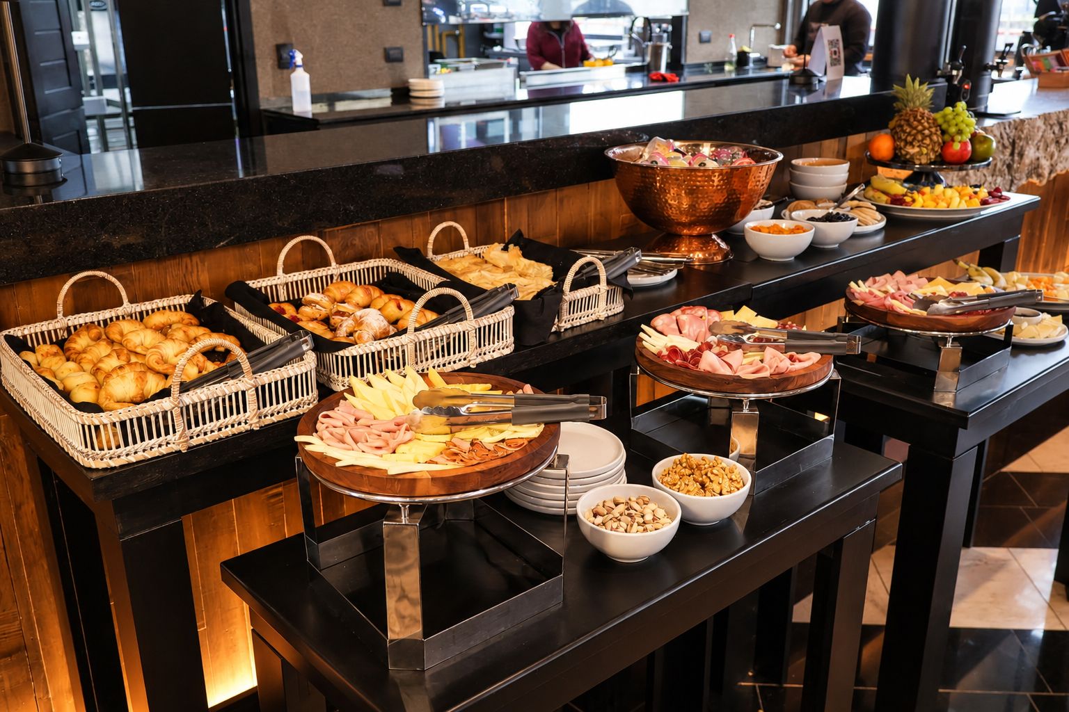 Een buffet met diverse gerechten, waaronder gebak, vleeswaren en fruit.