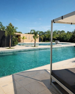 A swimming pool with clear water, surrounded by palm trees and a modern building. - Radisson RED Funes (Funes)