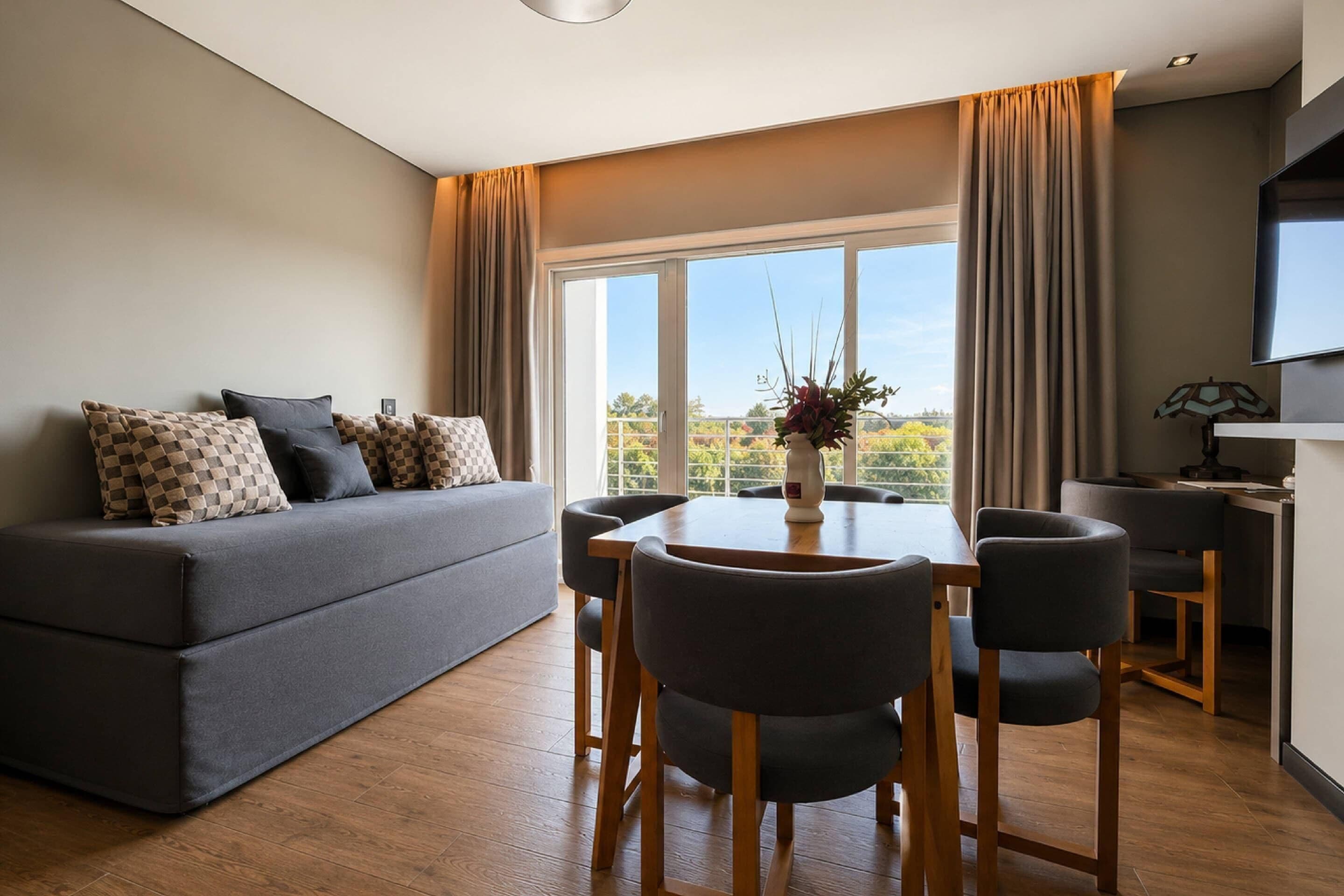 A modern living room with a sofa, dining table, chairs, and a TV.