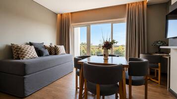 A modern living room with a sofa, dining table, chairs, and a TV.