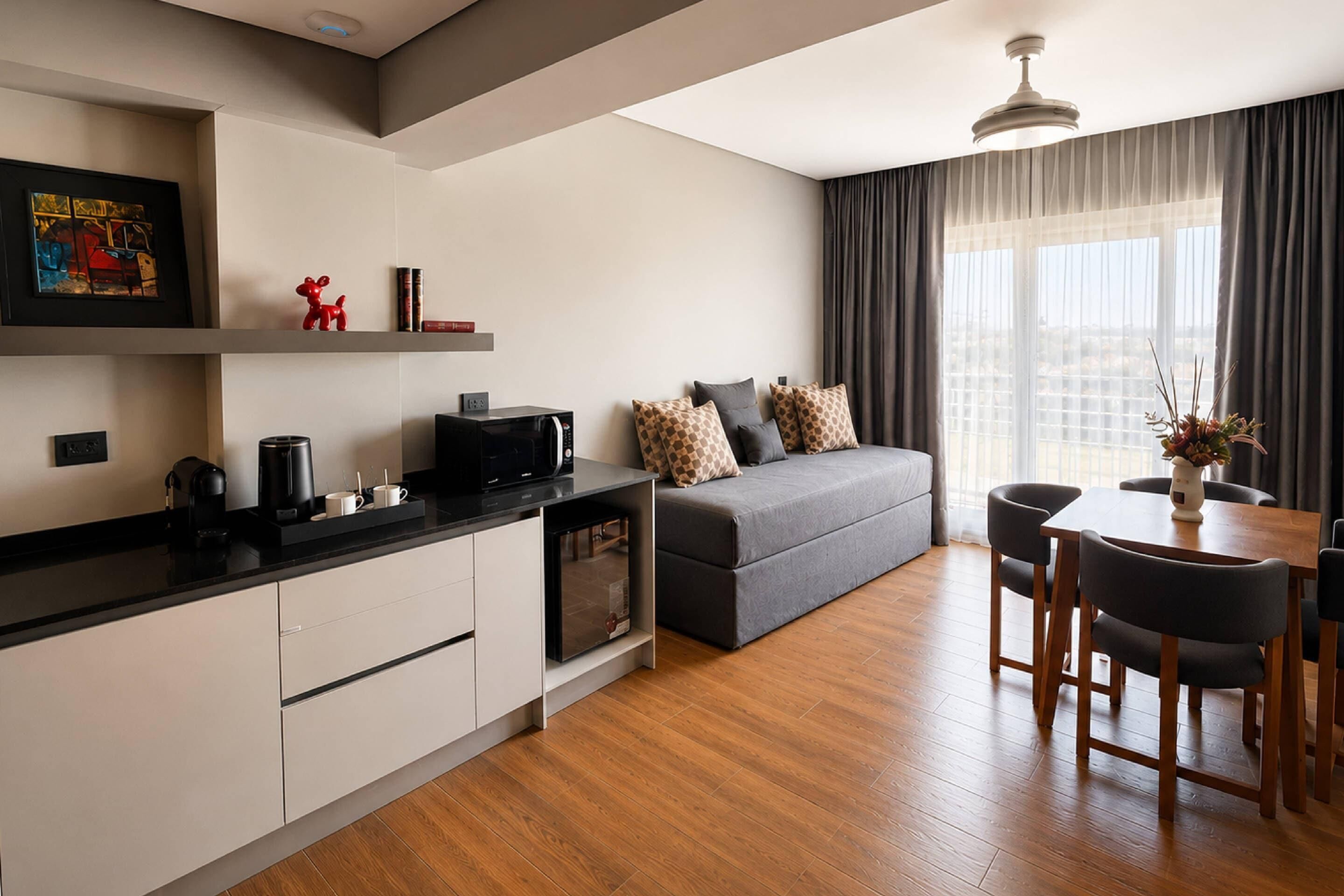 A modern living room with a sofa, dining table, and kitchen area.