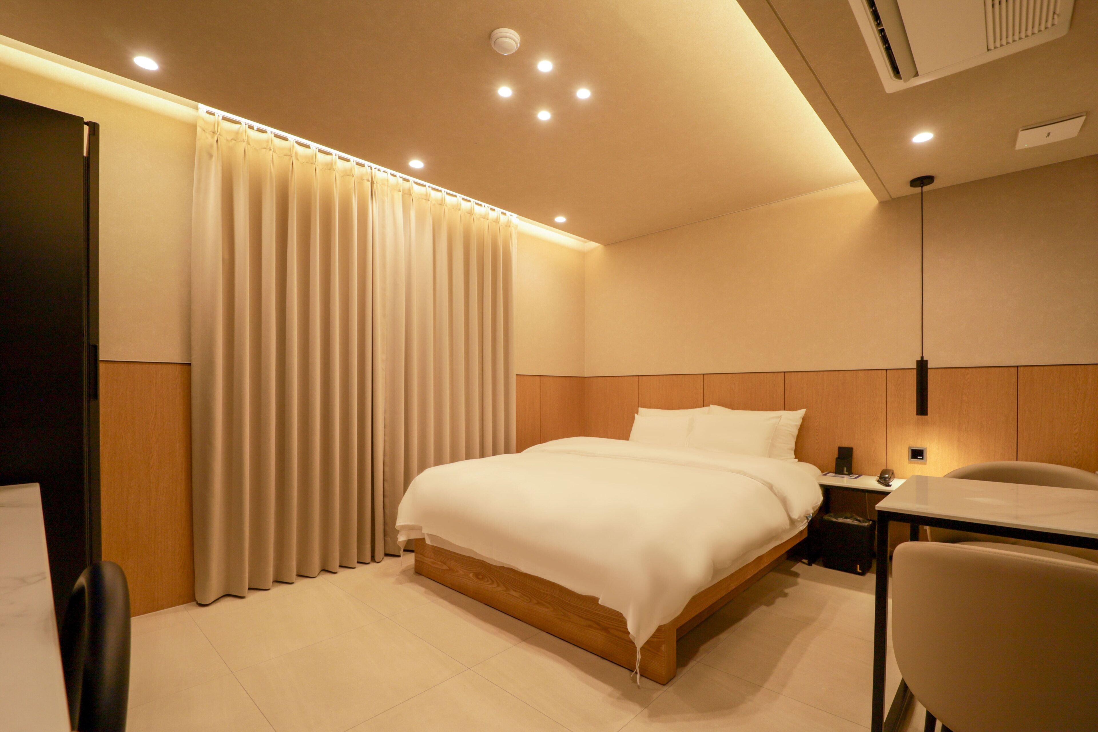 Une chambre d’hôtel avec un lit, un bureau, une chaise et un rideau.