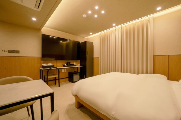 A hotel room with a bed, desk, chair, and a television. - Lounge Hotel (Seoul)
