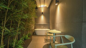Une salle de bain moderne avec une baignoire sur pieds, une petite table ronde et des chaises, le tout entouré de plantes en bambou.