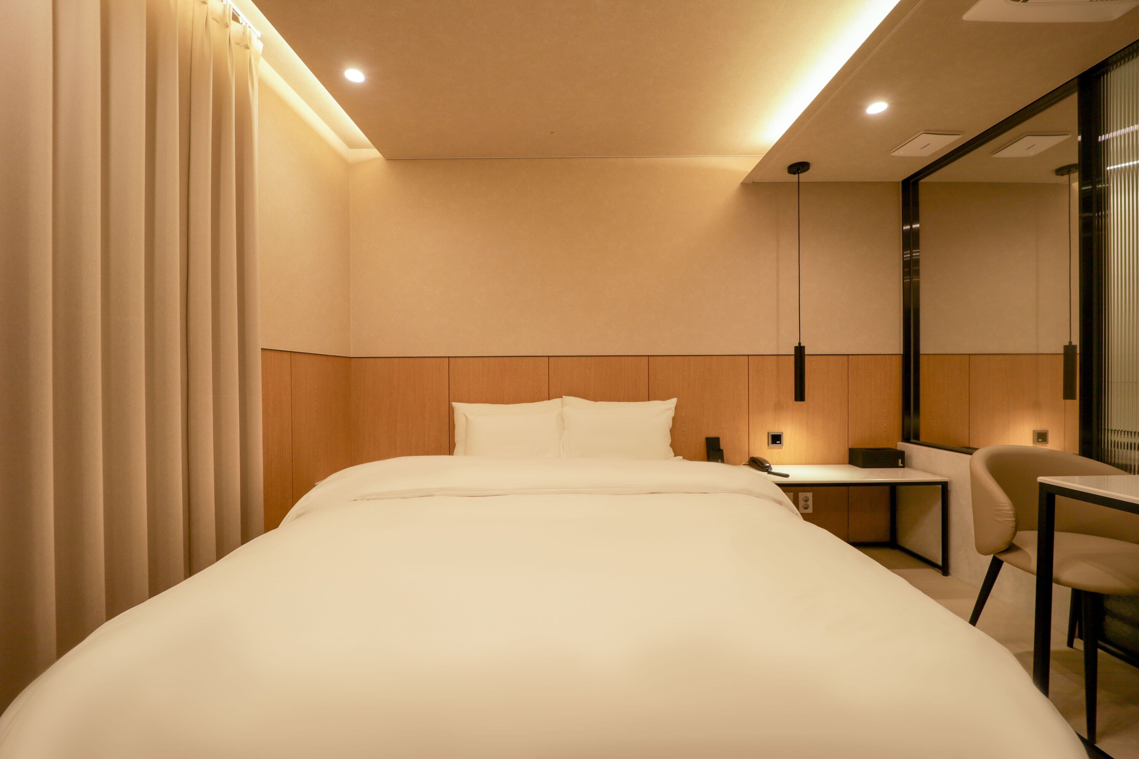Una habitación de hotel con cama, escritorio, silla y espejo.