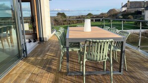 Um deck de madeira com mesa e cadeiras, com vista para uma paisagem deslumbrante.