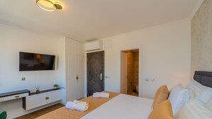 Hotellihuone, jossa on suuri sänky, työpöytä ja tasatelevisio sekä ovi, joka johtaa kylpyhuoneeseen.