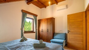 A bedroom with a bed, a wardrobe, a chair, and a window with curtains. - Villa Brusiana With Covered Heated Pool (Gospic)