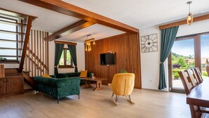 A spacious living area with a wooden staircase, a green sofa, a yellow chair, and a dining table. - Villa Brusiana With Covered Heated Pool (Gospic)