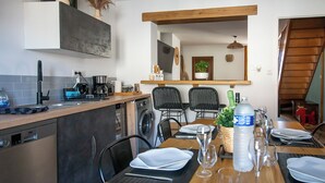 A modern kitchen with a dishwasher, sink, and a dining area set up with a table, chairs, and a bottle of water. - THE CHARM OF LES BERCEAUX: 5 minutes from Avenue de Champagne and right in the heart of the city (Épernay)
