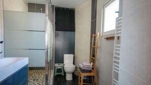 A bathroom with a bathtub, toilet, and a small wooden chair with towels. - THE CHARM OF LES BERCEAUX: 5 minutes from Avenue de Champagne and right in the heart of the city (Épernay)