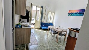 Un espace de vie compact comprenant un coin cuisine, un espace repas et un canapé.