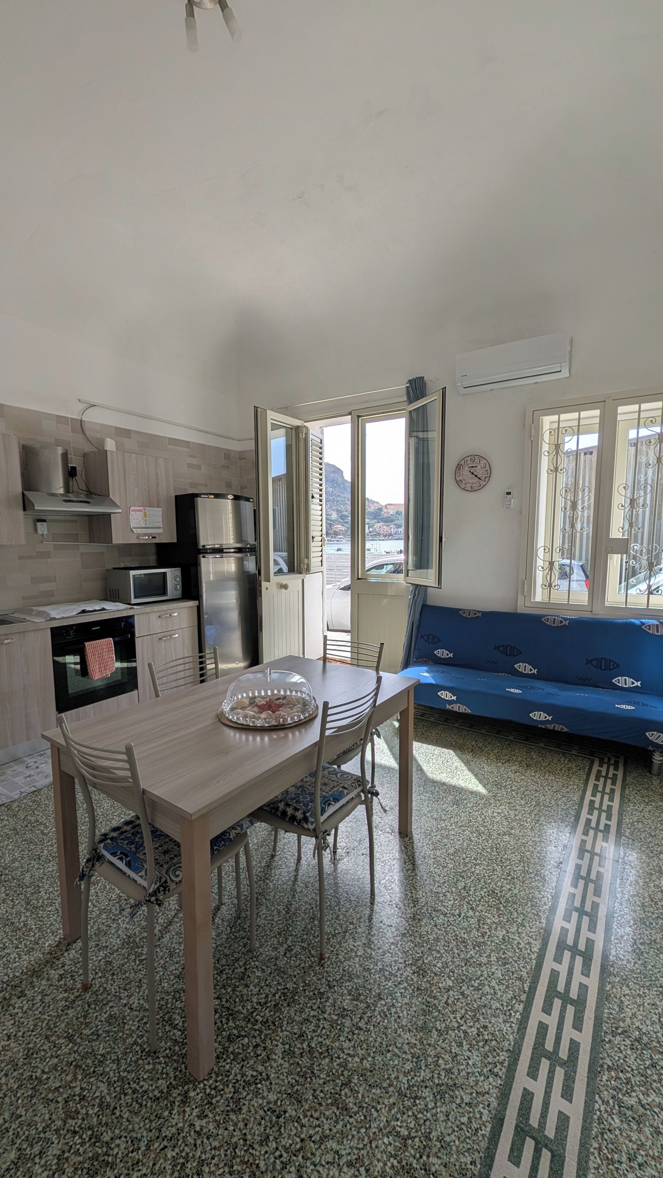 Una cocina moderna con comedor, un sofá azul y vistas al exterior.