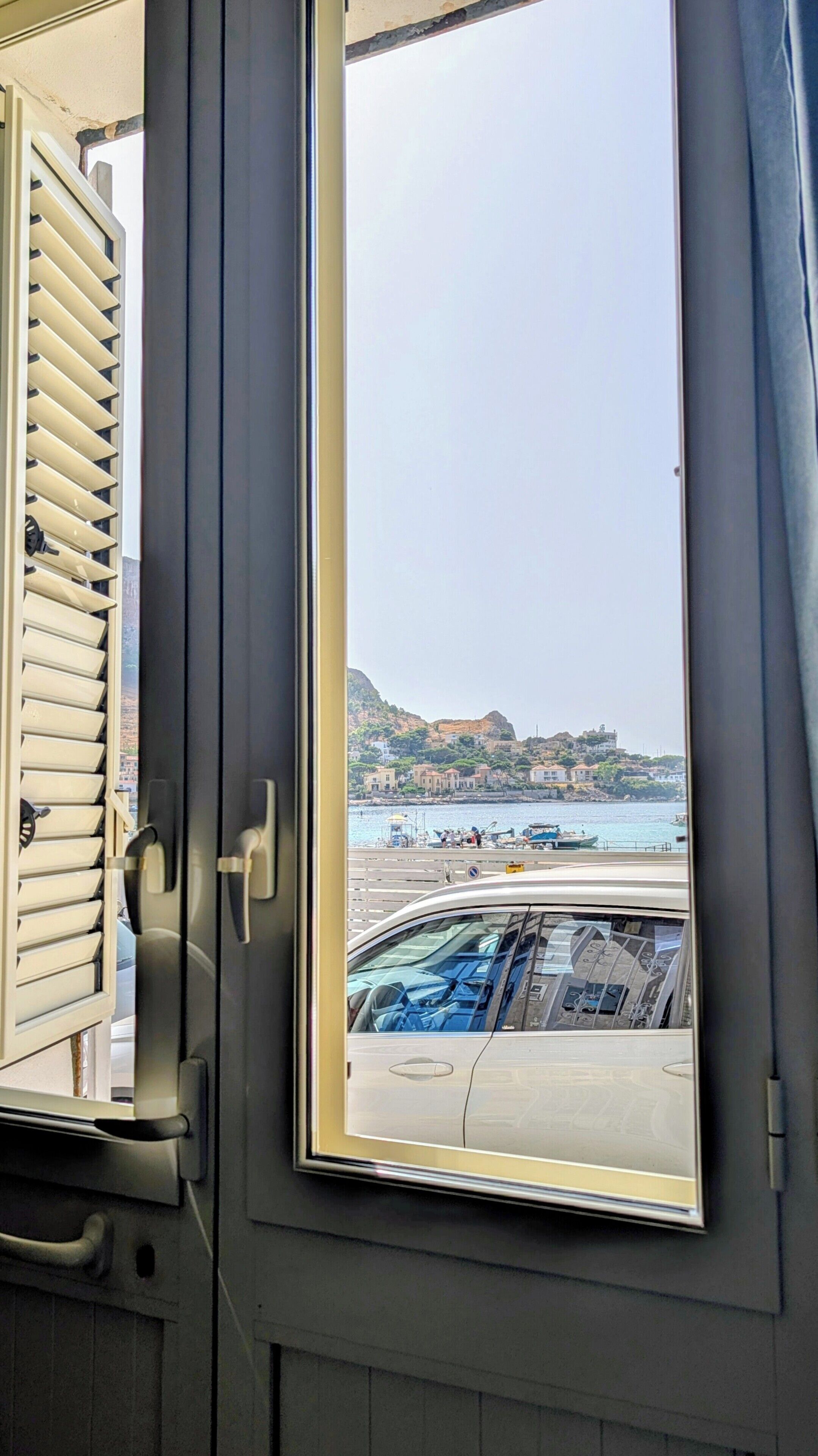 A vehicle interior with a view of a coastal area through an open window.