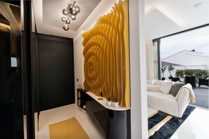Ein modernes Interieur mit geschwungenen Wänden, einem weißen Sofa und einem großen Fenster mit Blick ins Freie.