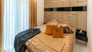 Una cama bien hecha con una manta color beige, dos bolsos marrones y dos bolsas de compras marrones sobre la cama.