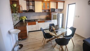 Een moderne keuken met houten kastjes, een magnetron en een koelkast. Er is een eettafel met stoelen en een vaas met bloemen.