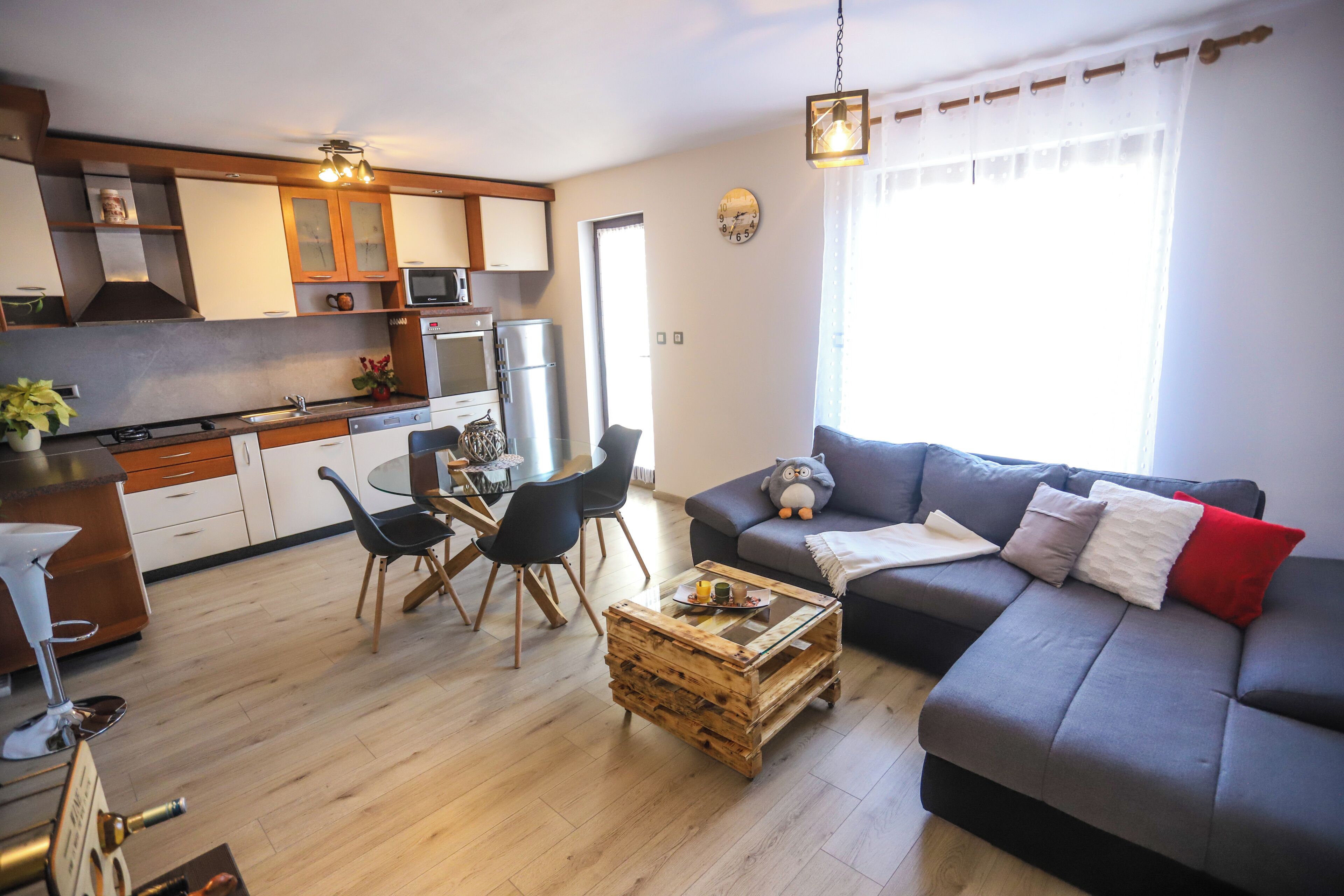 A modern living room with a grey sofa, wooden coffee table, and a dining area with a table and chairs.