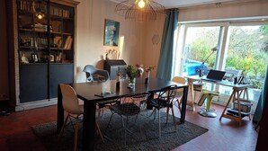 Zona pranzo con tavolo, sedie, un computer portatile e una libreria.