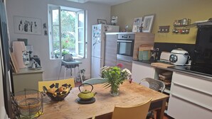 Una cucina con un tavolo di legno, sedie, un frigorifero, un forno e un microonde.