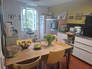 A kitchen with a wooden table, chairs, a refrigerator, an oven, and a microwave. - AU 15 : charming house with garden, 3 bedrooms 3 bathrooms 6 km from the beach, animals ok (Quettreville-sur-Sienne)