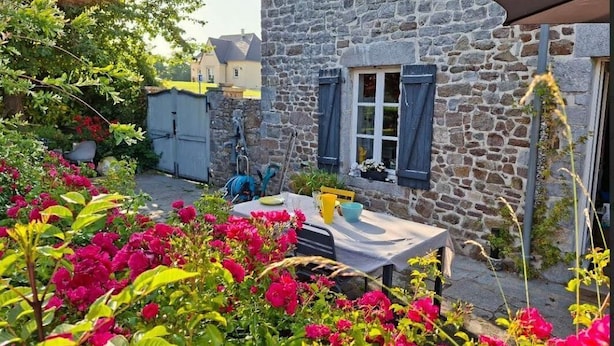 Un edificio in pietra con un tavolo e sedie all'esterno, circondato da fiori colorati.